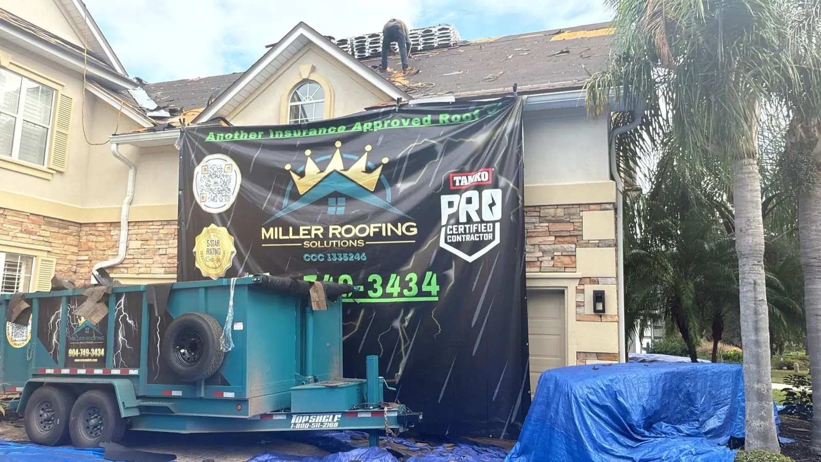 Miller Roofing Solutions banner reading Another Insurance Approved Roof with the TAMKO contractor badge, hung on a home during a roof replacement