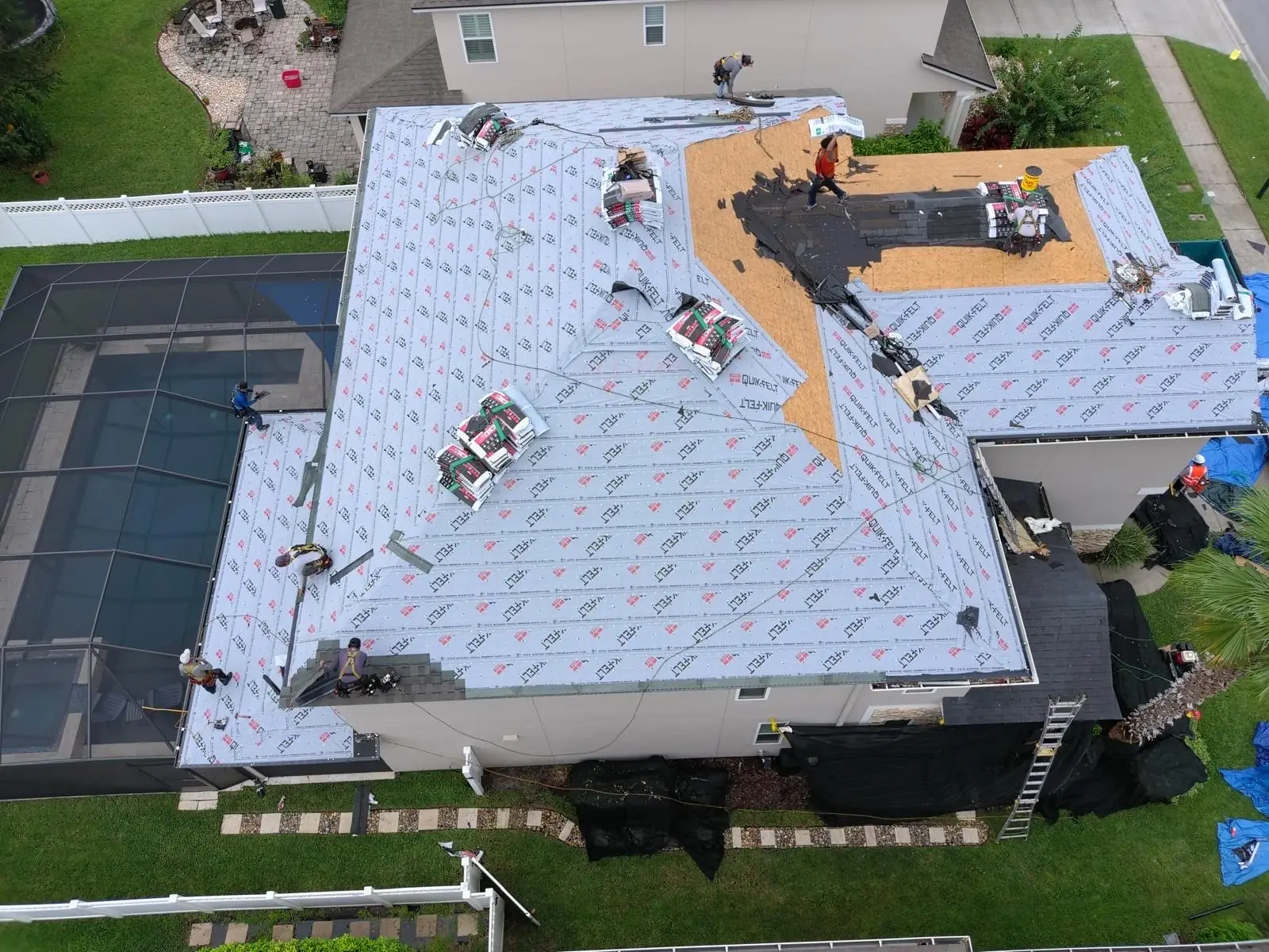 Aerial view of a fully dried-in roof over a pool enclosure, crew at the ridge